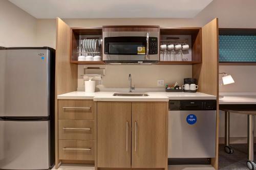 a kitchen with a refrigerator and a microwave at Home2 Suites By Hilton Carmel Indianapolis in Carmel