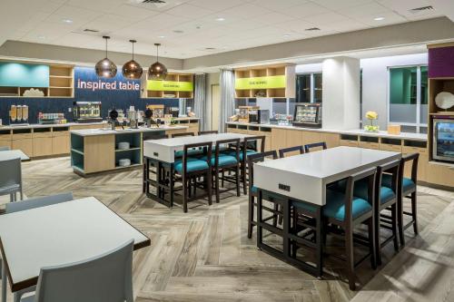a restaurant with tables and chairs in a cafeteria at Home2 Suites By Hilton Cape Canaveral Cruise Port in Cape Canaveral