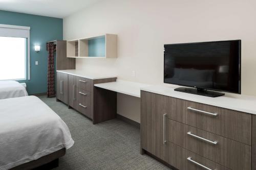 a hotel room with a bed and a flat screen tv at Home2 Suites By Hilton Cape Canaveral Cruise Port in Cape Canaveral