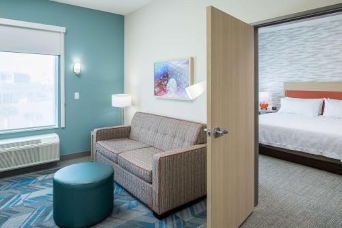 a hotel room with a chair and a bed at Home2 Suites By Hilton Cape Canaveral Cruise Port in Cape Canaveral