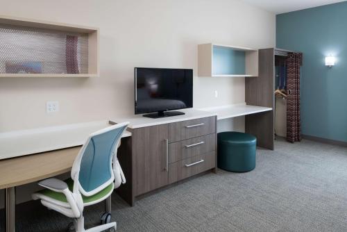 an office with a desk with a tv and a chair at Home2 Suites By Hilton Cape Canaveral Cruise Port in Cape Canaveral
