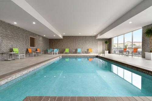 a pool in a hotel with chairs and tables at Home2 Suites By Hilton Norfolk Airport in Norfolk