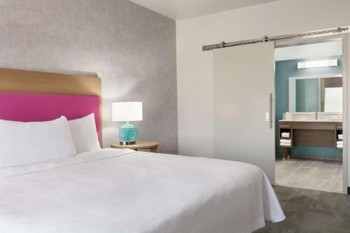 a bedroom with a bed and a bathroom with a sink at Home2 Suites By Hilton Norfolk Airport in Norfolk