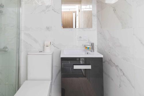 Un baño blanco con lavabo y espejo. en Sunset Bungalow, en San Bartolomé