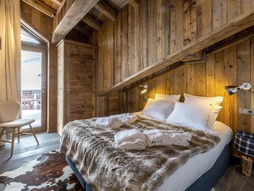 une chambre avec un grand lit avec un mur en bois dans l'établissement Appartement de luxe au dernier étage, matériaux nobles, résidence aux pieds des pistes, Val-d'Isère - FR-1-694-89, à Val dʼIsère