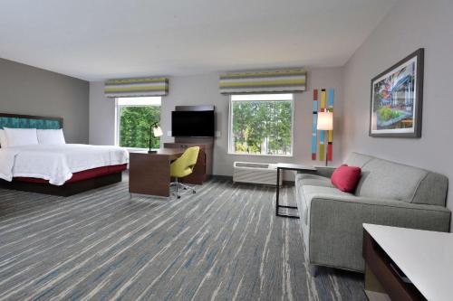 Habitación de hotel con cama y sofá en Hampton Inn & Suites Charlotte North I 485 en Charlotte
