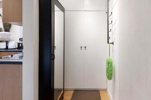 a kitchen with white cabinets and a door with a green plant at Boutique Apartment Anybody in Gaienhofen