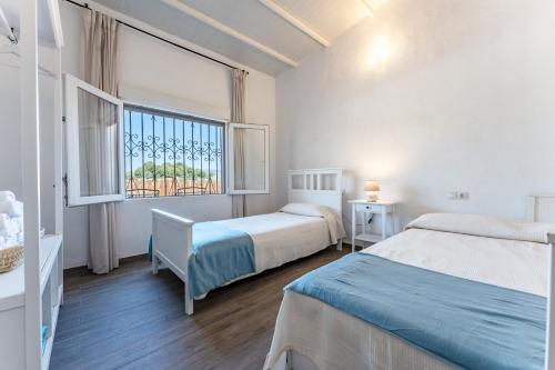 a bedroom with two beds and a window at Cortijo La Zahurdilla in Yunquera