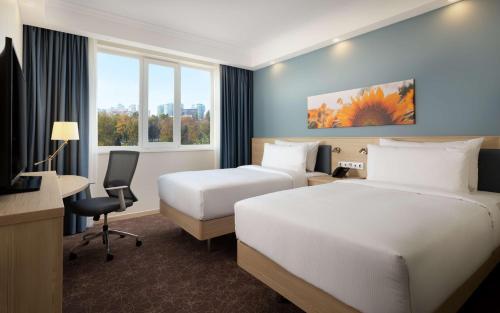 a hotel room with two beds and a desk at Hampton By Hilton Krasnodar in Krasnodar