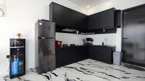 - une cuisine avec des armoires noires et un réfrigérateur dans l'établissement Mountain Hill, à Songgoriti