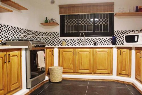 a kitchen with wooden cabinets and black and white tiles at cozy studio in cite ennasr 1 in Ariana