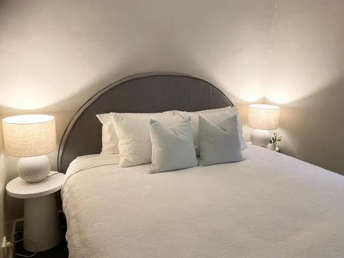 un letto con cuscini bianchi e 2 lampade sopra di Angaston Mews Apartments ad Angaston
