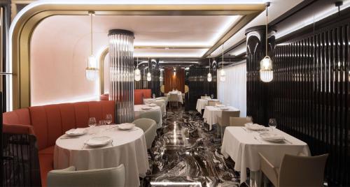 un comedor con mesas blancas y sillas rojas en DoubleTree By Hilton A Coruña en A Coruña