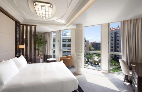 a bedroom with a large white bed and large windows at DoubleTree By Hilton A Coruña in A Coruña