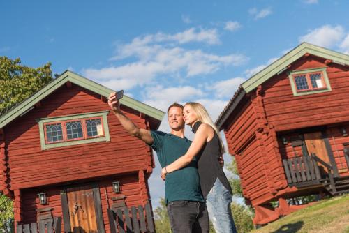 Ein Mann und eine Frau stehen vor einem roten Haus. in der Unterkunft Green Hotel in Tällberg