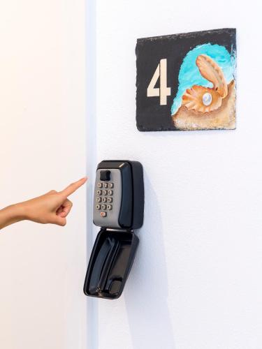 a person pointing at a cell phone hanging on a wall at Hostal Perla Blanca Altea in Altea