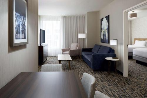 a living room with a blue couch and a bed at Homewood Suites By Hilton Montreal Midtown in Montreal