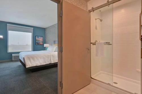 a bedroom with a bed and a glass shower at Home2 Suites Corpus Christi Southeast, Tx in Corpus Christi