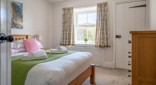 a bedroom with a bed with two towels on it at Eel House Cottage in Sawrey