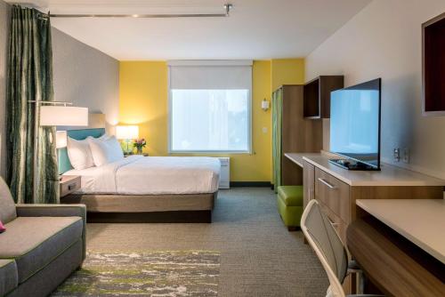 a hotel room with a bed and a flat screen tv at Home2 Suites By Hilton Memphis East / Germantown, Tn in Memphis