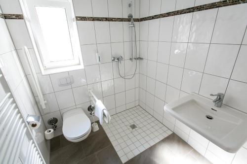 een witte badkamer met een toilet en een wastafel bij Heilbronner Pension am schönen Theater in Heilbronn