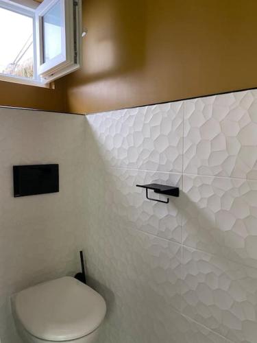 une salle de bain avec des toilettes blanches et une fenêtre dans l'établissement Très bel appartement avec jardin reposant, à Angers