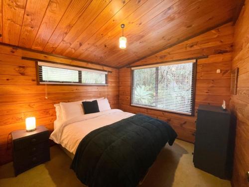 um quarto com uma cama num chalé de madeira em Hekerua Bay Views Oneroa - Waiheke Escapes em Oneroa
