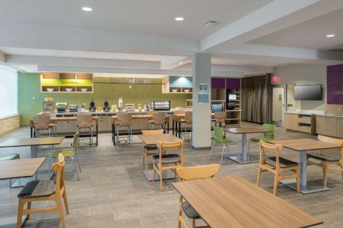 a restaurant with tables and chairs and a cafeteria at Home2 Suites by Hilton Fort Worth Cultural District in Fort Worth