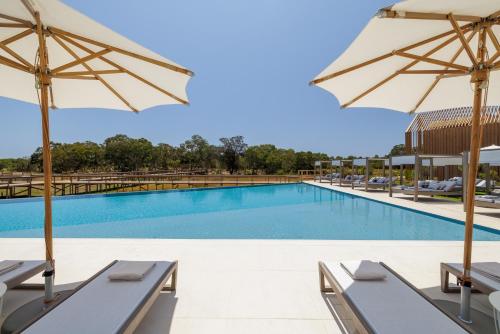a swimming pool with chairs and umbrellas at Verdelago Resort in Praia Verde