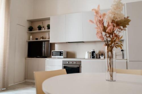 a kitchen with white cabinets and a table with flowers at La casetta del SI minore in Bari