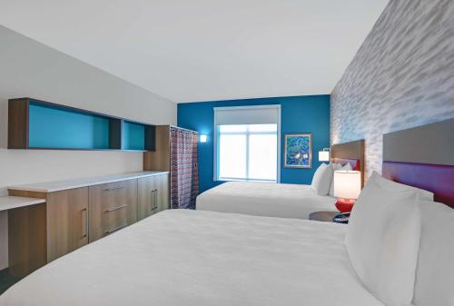 a bedroom with two beds and blue walls at Home2 Suites By Hilton Melbourne Viera in Melbourne