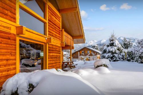 eine Blockhütte im Schnee mit schneebedeckten Bäumen in der Unterkunft Chalet Antigone - OVO Network in Saint-Jean-de-Sixt