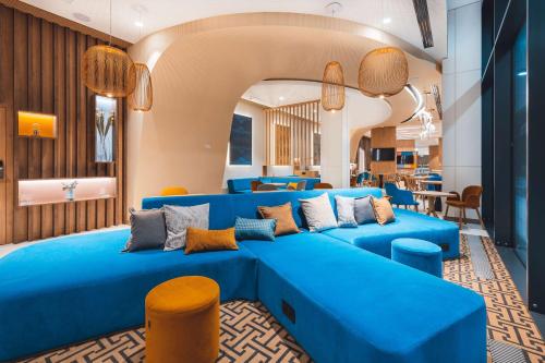 a large blue couch in a room with chairs at Hampton By Hilton Warsaw Reduta in Warsaw
