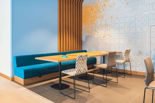 a dining room with a blue couch and a table and chairs at Hampton By Hilton Warsaw Reduta in Warsaw