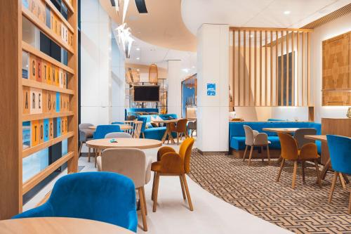 a library with tables and chairs and a tv at Hampton By Hilton Warsaw Reduta in Warsaw