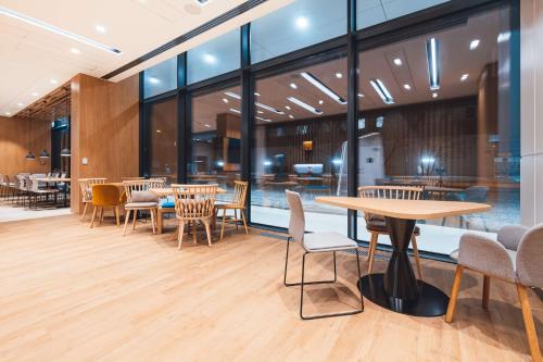 a cafeteria with tables and chairs and windows at Hampton By Hilton Warsaw Reduta in Warsaw