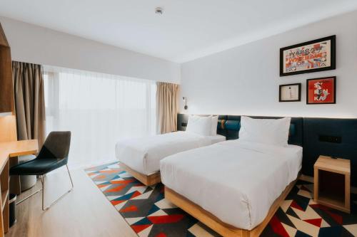a hotel room with two beds and a chair at Hampton By Hilton Warsaw Reduta in Warsaw