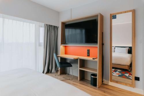 a bedroom with a bed and a desk with a television at Hampton By Hilton Warsaw Reduta in Warsaw