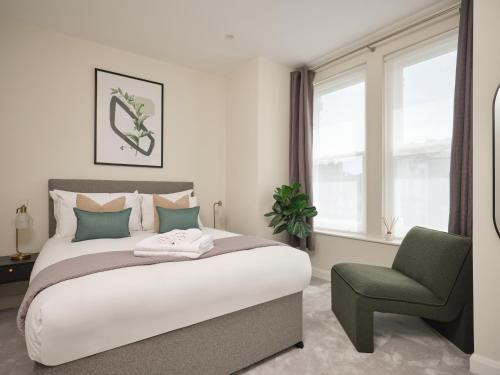 a bedroom with a large bed and a green chair at Fulham - Hestercombe House by Viridian Apartments in London