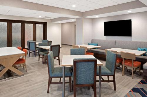 a waiting room with tables and chairs and a flat screen tv at Hampton Inn Circleville, Oh in Circleville