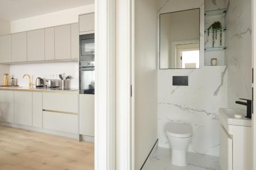 a white bathroom with a toilet and a sink at Fulham - Hestercombe House by Viridian Apartments in London