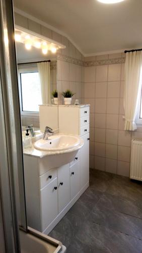a white bathroom with a sink and a mirror at Ferienwohnung Achterdeck - Alte Schmiede Neugarmssiel in Wangerland