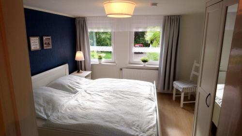 a bedroom with a white bed and a blue wall at Ferienwohnung Achterdeck in Wangerland