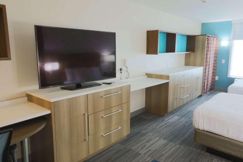 a hotel room with a flat screen tv and a bed at Home2 Suites By Hilton Cumming Atlanta, Ga in Cumming