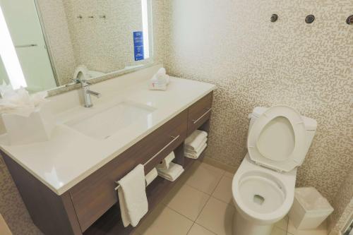 a bathroom with a sink and a toilet and a mirror at Home2 Suites By Hilton Cumming Atlanta, Ga in Cumming