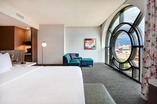 Hilton Garden Inn Kalamazoo Downtown في كالامازو: غرفة فندقية بسرير كبير ونافذة