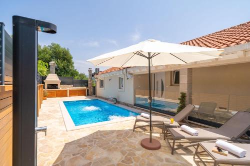 - une piscine avec des chaises et un parasol à côté d'une maison dans l'établissement Villa Tranquility Nest Beniva, à Mokošica