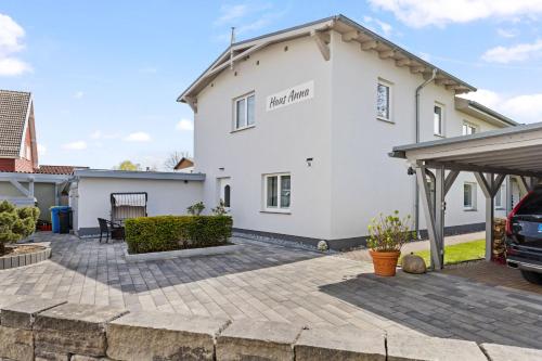 ein weißes Haus mit einer Terrasse davor in der Unterkunft Ferienwohnungen Haus Anna OFC 26 in Kühlungsborn