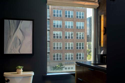 a bathroom with a toilet and a window with a building at The Lloyd Stamford, Tapestry Collection by Hilton in Stamford