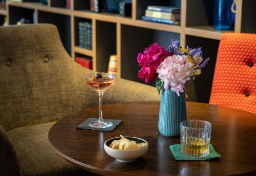 a table with a vase of flowers and a glass of wine at Leonardo Royal Hotel Brighton Waterfront in Brighton & Hove